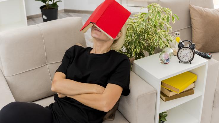 Mujer recostada en el sillón con un libro en la cara